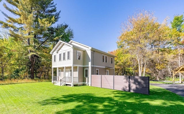 rear view of property with a lawn, fence, and covered porch