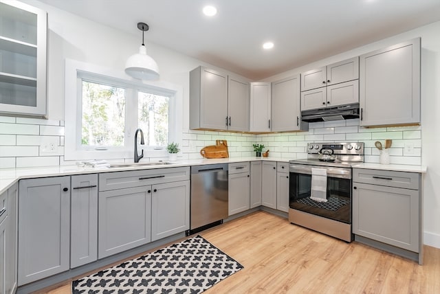 kitchen with gray cabinets, light hardwood / wood-style flooring, decorative light fixtures, sink, and appliances with stainless steel finishes