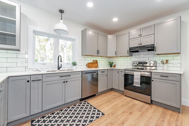kitchen featuring under cabinet range hood, stainless steel appliances, and gray cabinetry