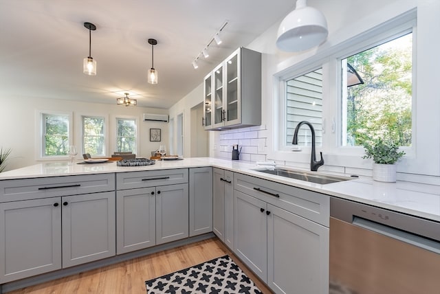 kitchen with stainless steel dishwasher, sink, light hardwood / wood-style floors, gray cabinets, and decorative light fixtures