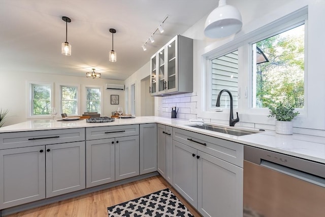 kitchen with a sink, a peninsula, dishwasher, and gray cabinetry