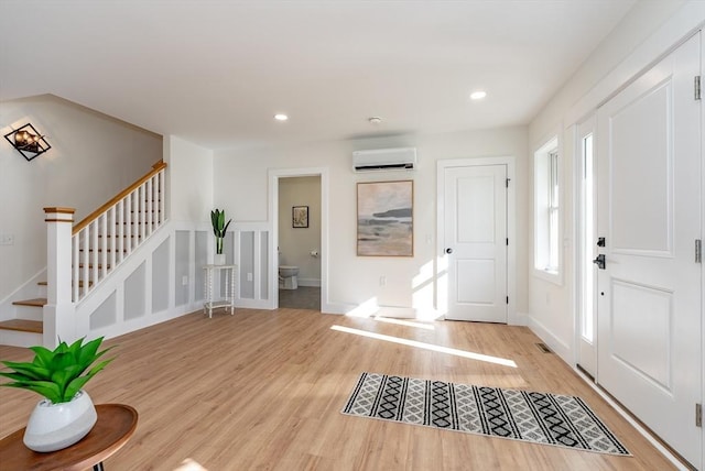entryway with stairs, recessed lighting, a wall unit AC, and light wood-style flooring