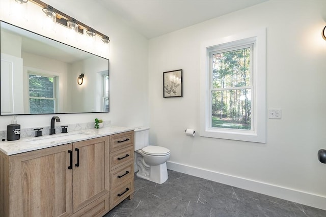 bathroom with baseboards, toilet, and vanity