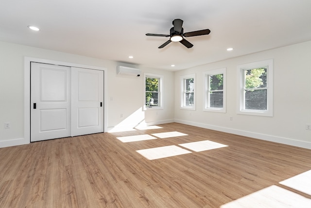 unfurnished room featuring an AC wall unit, light wood-type flooring, and ceiling fan