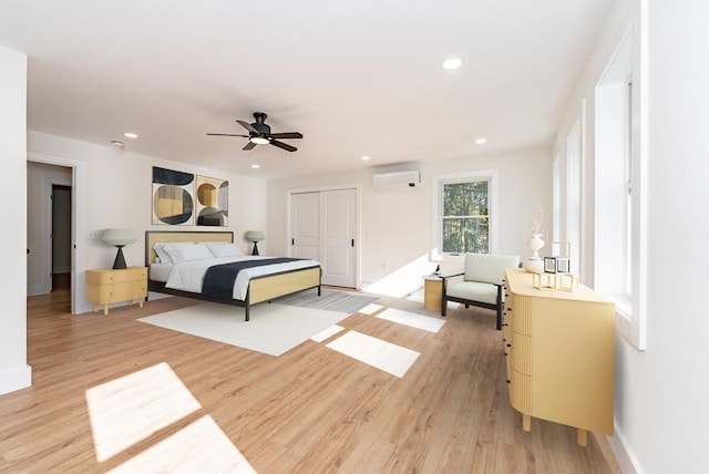 bedroom with light wood-style floors, recessed lighting, baseboards, a wall unit AC, and a closet