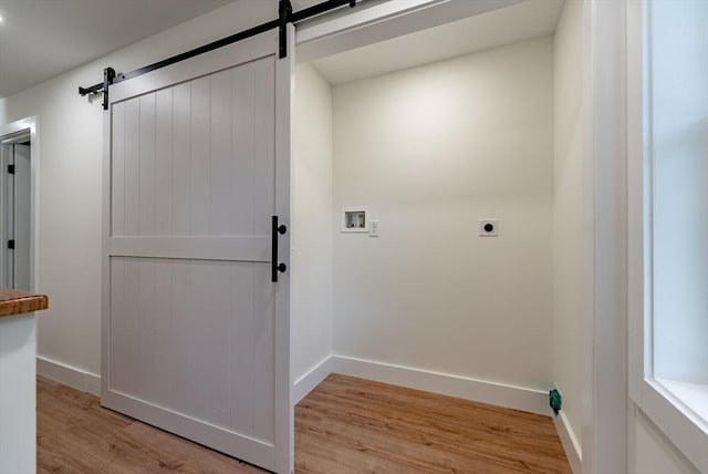 washroom with hookup for an electric dryer, a barn door, baseboards, hookup for a washing machine, and light wood-style flooring