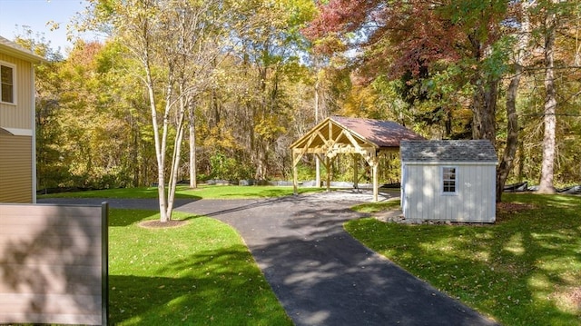 view of community with a storage shed, a yard, and an outdoor structure