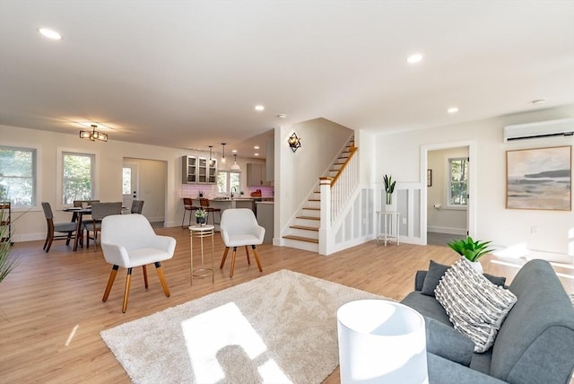living area with recessed lighting, light wood-style flooring, stairway, and a wall mounted air conditioner