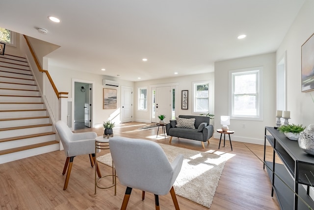 living room with light hardwood / wood-style flooring and a wall unit AC