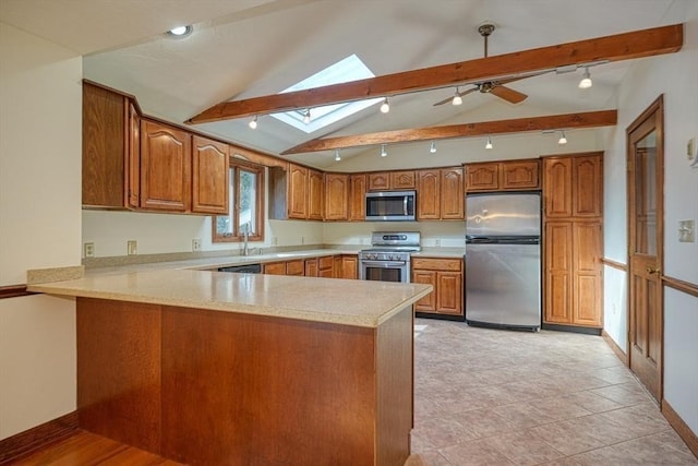 kitchen with brown cabinets, vaulted ceiling with skylight, a peninsula, and stainless steel appliances