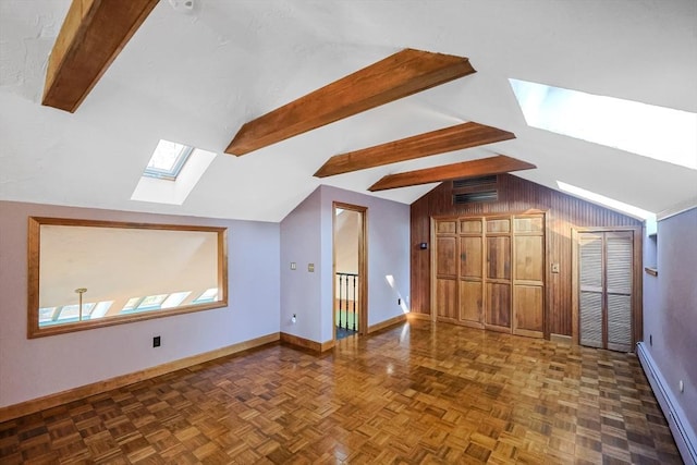 bonus room with dark parquet floors, baseboard heating, wood walls, and vaulted ceiling with skylight