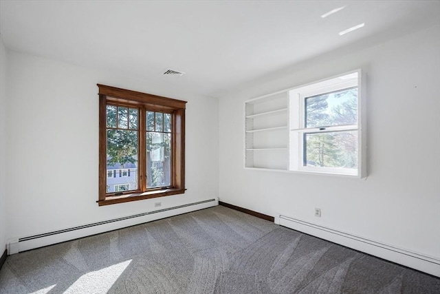 spare room featuring carpet, built in shelves, and a baseboard heating unit