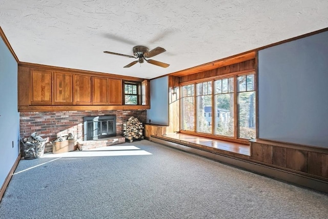 unfurnished living room with carpet flooring, baseboard heating, ceiling fan, and ornamental molding