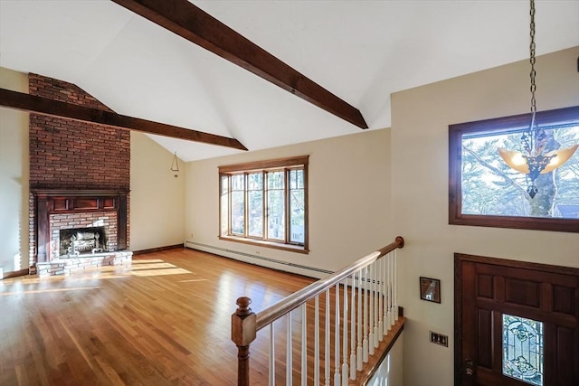 interior space featuring vaulted ceiling with beams, a fireplace, an inviting chandelier, and light hardwood / wood-style flooring