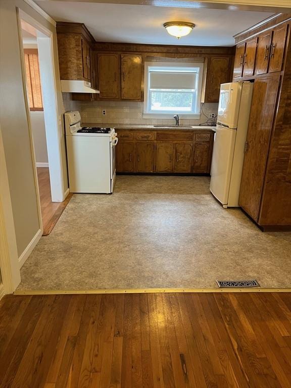 kitchen with white appliances, under cabinet range hood, backsplash, and light wood-style floors