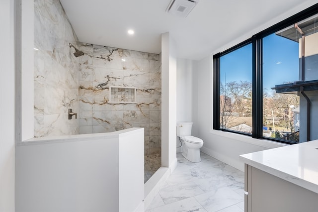 bathroom with vanity, tile floors, toilet, and tiled shower