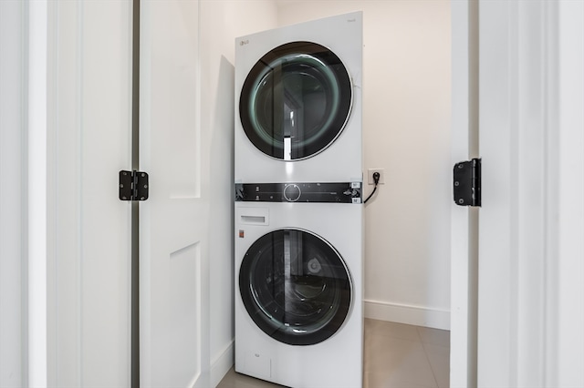 clothes washing area featuring stacked washer and dryer and light tile floors