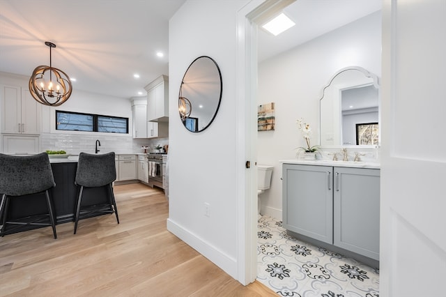 bathroom featuring toilet, a chandelier, wood-type flooring, tasteful backsplash, and large vanity