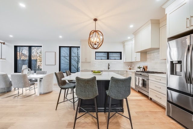 kitchen with tasteful backsplash, stainless steel appliances, light wood-type flooring, and a breakfast bar