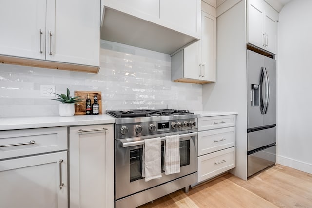 kitchen featuring white cabinetry, appliances with stainless steel finishes, tasteful backsplash, and light hardwood / wood-style floors