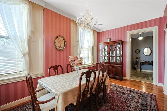 dining room with hardwood / wood-style floors, ornamental molding, and a notable chandelier