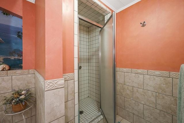 bathroom with tile walls, a shower with door, and ornamental molding