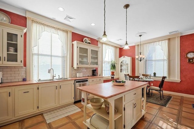 kitchen featuring tasteful backsplash, light tile patterned flooring, dishwasher, pendant lighting, and sink