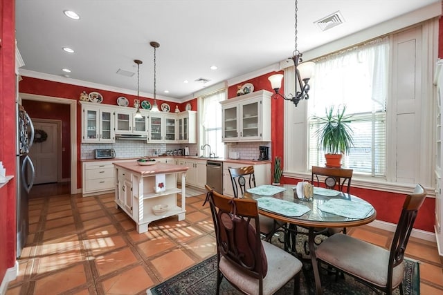 kitchen featuring stainless steel dishwasher, a center island, wood counters, and pendant lighting