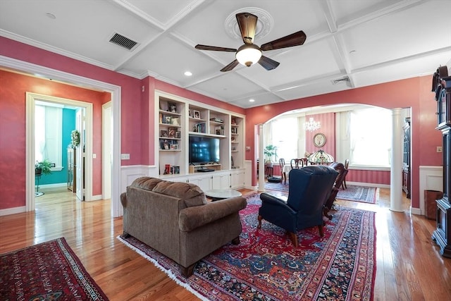 living room with ceiling fan with notable chandelier, beamed ceiling, ornamental molding, light wood-type flooring, and coffered ceiling