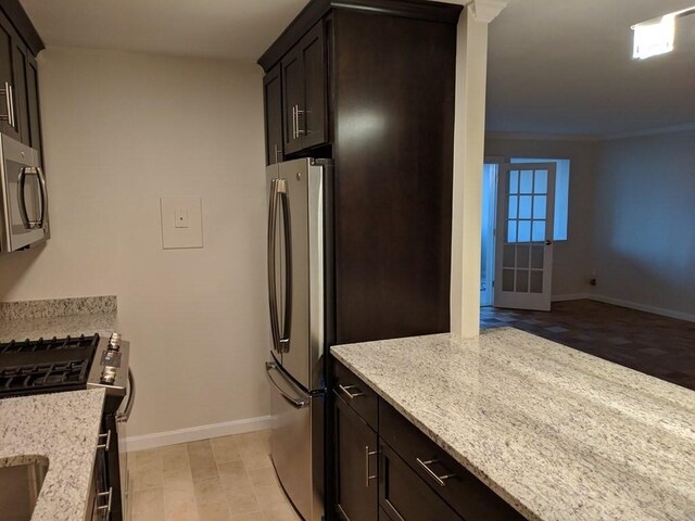kitchen with appliances with stainless steel finishes, baseboards, light stone countertops, and dark brown cabinets