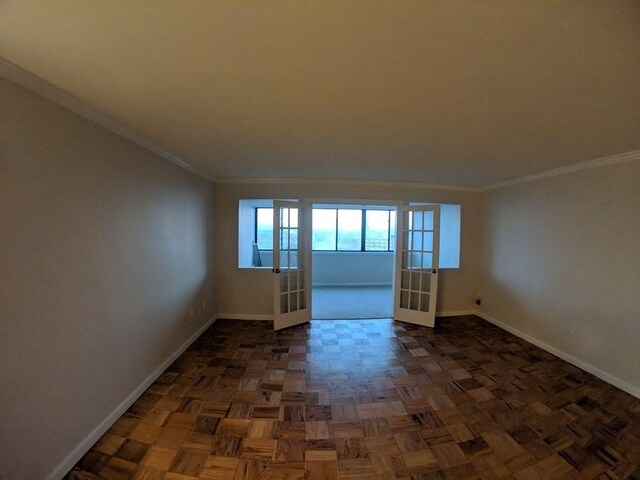 empty room featuring baseboards, ornamental molding, and french doors