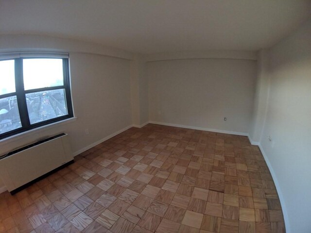 spare room with baseboards and radiator