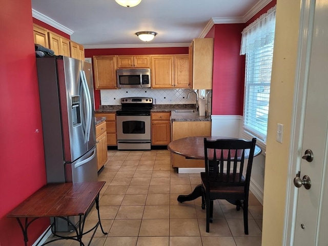 kitchen with light tile patterned floors, a sink, appliances with stainless steel finishes, dark countertops, and crown molding