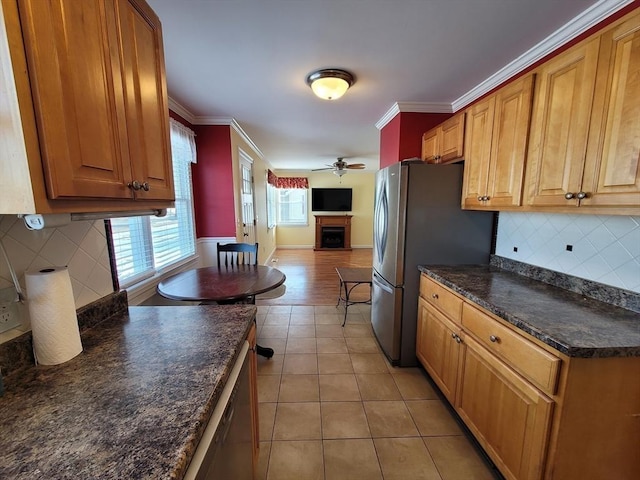 kitchen featuring ornamental molding, dark countertops, a fireplace, and appliances with stainless steel finishes