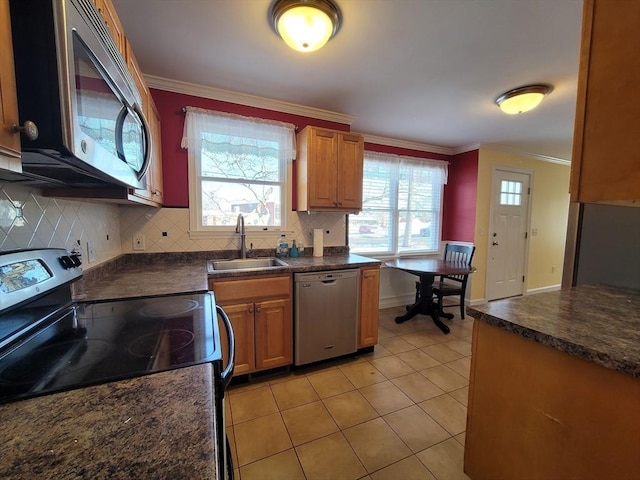 kitchen with dark countertops, ornamental molding, stainless steel appliances, and a sink