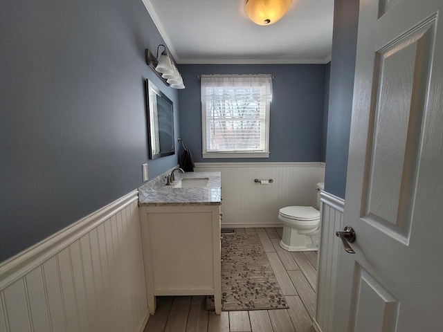 bathroom featuring toilet, a wainscoted wall, vanity, and wood finish floors