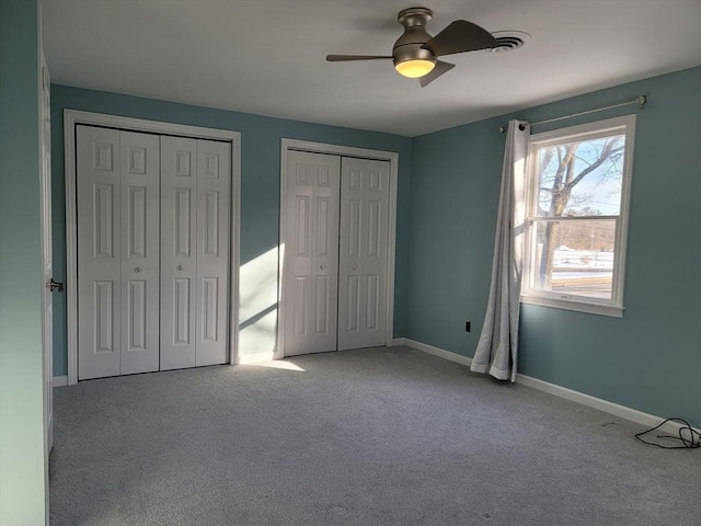 unfurnished bedroom with ceiling fan, baseboards, multiple closets, and carpet flooring