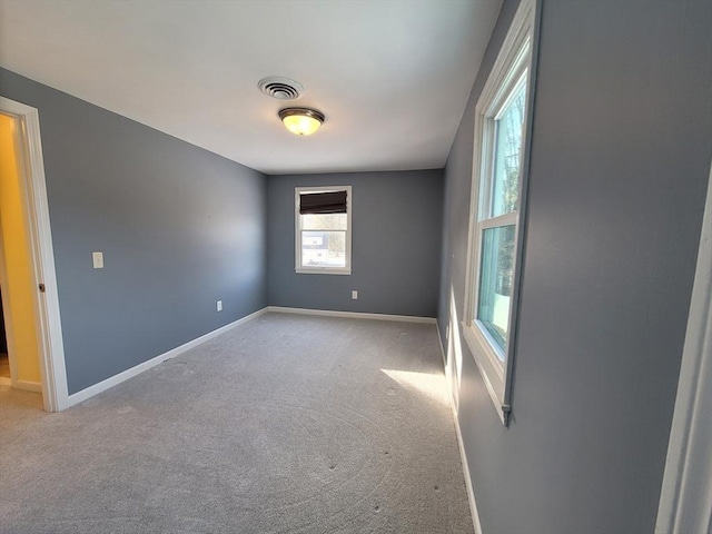 unfurnished room with carpet floors, visible vents, and baseboards