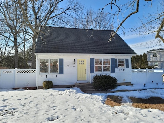 new england style home with roof with shingles and fence