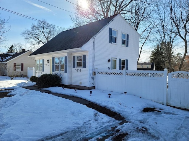 view of front of house with a shingled roof, a gate, and fence