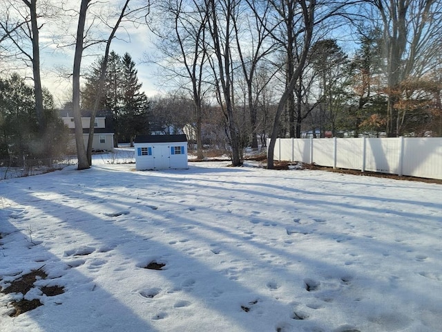 yard covered in snow featuring a shed, fence, and an outdoor structure