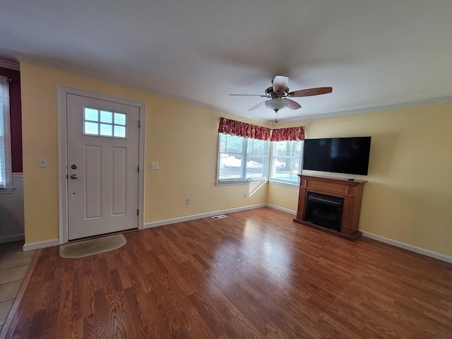 entrance foyer with a fireplace, crown molding, baseboards, and wood finished floors