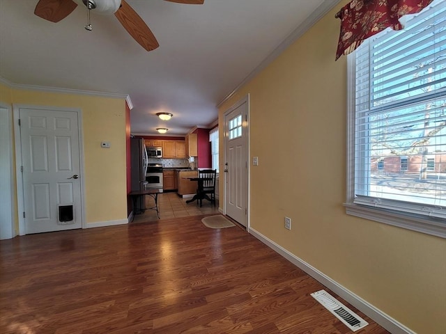 unfurnished living room featuring plenty of natural light, visible vents, and crown molding