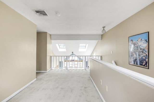 hall featuring visible vents, carpet floors, baseboards, and a skylight