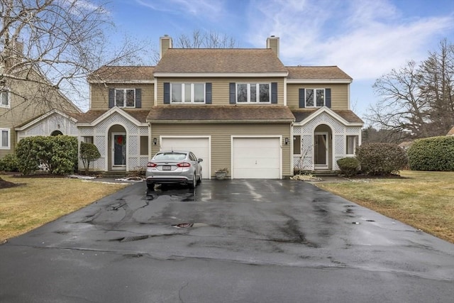 view of front of house featuring a garage, a front lawn, a chimney, and driveway