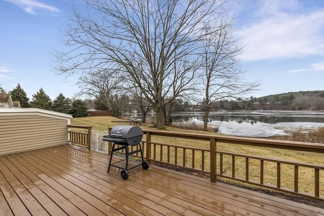 deck featuring grilling area, a water view, and a yard