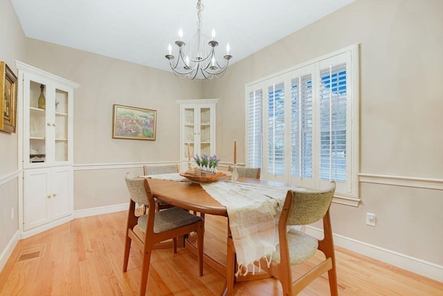 dining space with an inviting chandelier, light wood-style flooring, visible vents, and baseboards