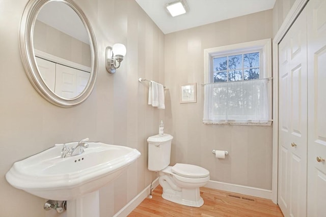 bathroom with visible vents, toilet, a sink, wood finished floors, and baseboards