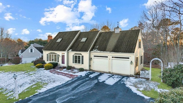 cape cod house featuring an attached garage, a chimney, and aphalt driveway