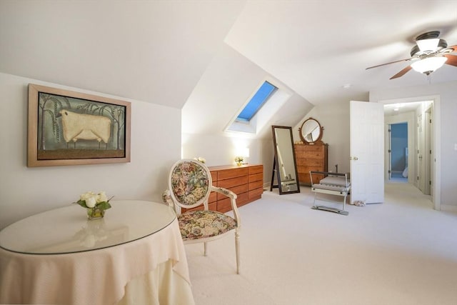 sitting room with lofted ceiling with skylight, carpet floors, and a ceiling fan